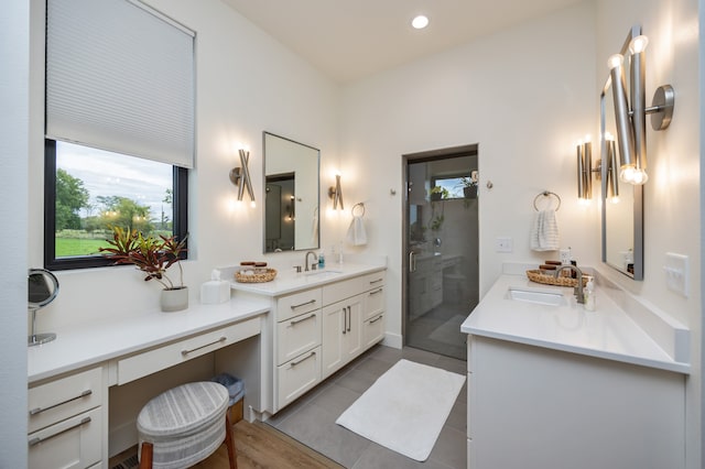 bathroom with a shower with door, vanity, and tile patterned floors