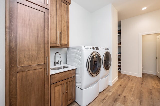 washroom featuring cabinets, sink, light hardwood / wood-style floors, and independent washer and dryer