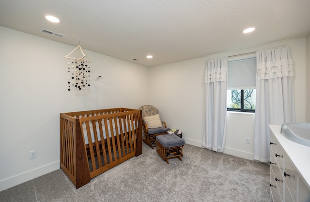 carpeted bedroom with sink and a nursery area