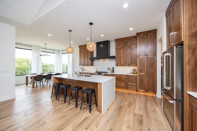 kitchen featuring appliances with stainless steel finishes, a kitchen breakfast bar, light wood-type flooring, custom exhaust hood, and a center island with sink