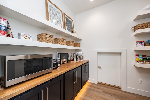 bar featuring light hardwood / wood-style floors and wooden counters