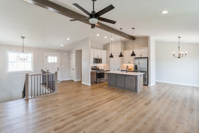 kitchen with vaulted ceiling with beams, a center island with sink, white cabinetry, appliances with stainless steel finishes, and ceiling fan with notable chandelier