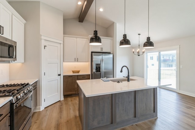 kitchen featuring white cabinets, a center island with sink, appliances with stainless steel finishes, and light wood-type flooring