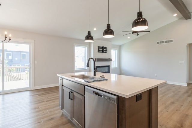 kitchen with an island with sink, sink, stainless steel dishwasher, lofted ceiling with beams, and light hardwood / wood-style floors