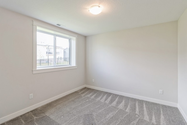 unfurnished room with a textured ceiling and carpet flooring