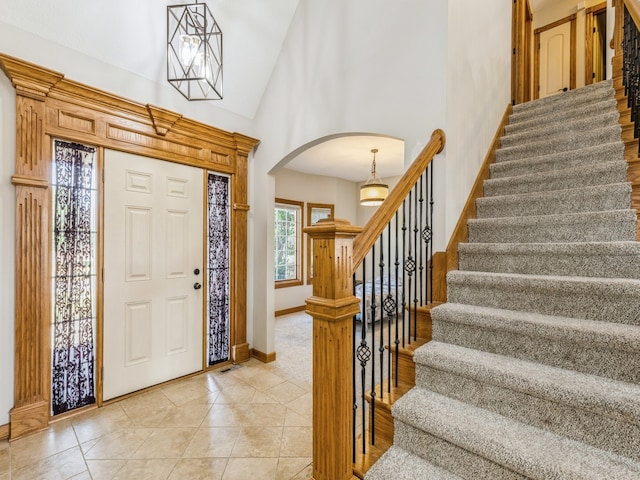 tiled entrance foyer featuring a notable chandelier and high vaulted ceiling