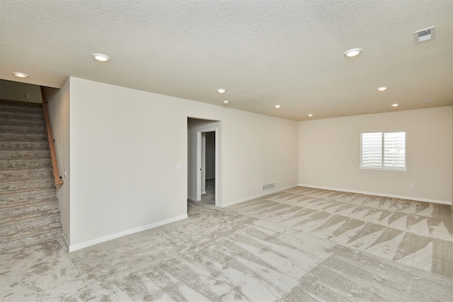 carpeted empty room featuring a textured ceiling