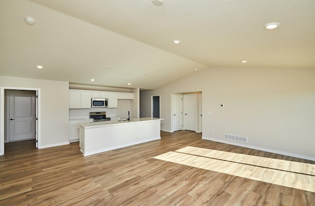 kitchen featuring sink, white cabinets, tasteful backsplash, a center island with sink, and stainless steel appliances