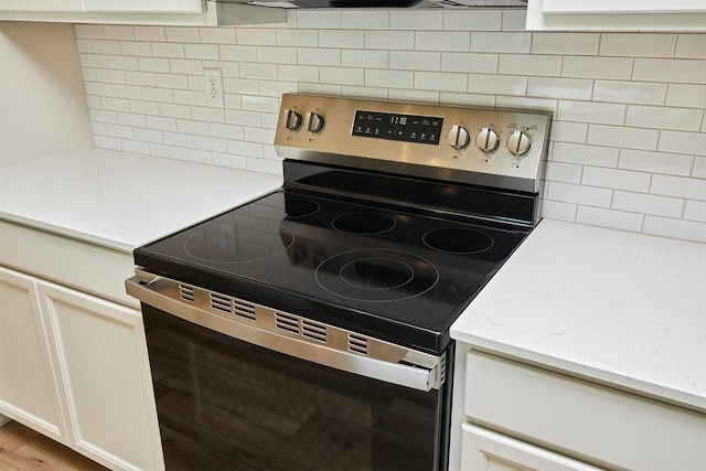 kitchen featuring stainless steel electric range oven, light hardwood / wood-style floors, and tasteful backsplash