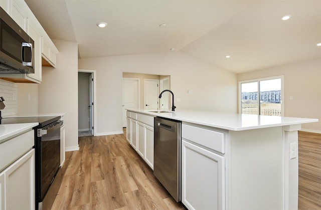 kitchen featuring appliances with stainless steel finishes, a kitchen island with sink, sink, white cabinets, and light hardwood / wood-style flooring