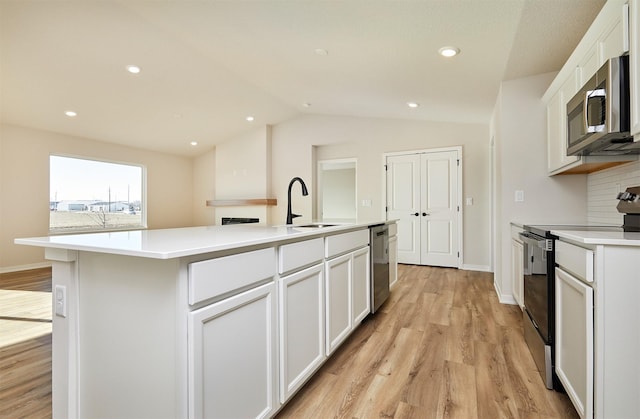 kitchen featuring sink, white cabinets, light hardwood / wood-style flooring, an island with sink, and stainless steel appliances