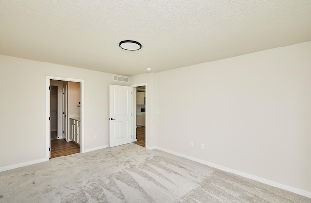 unfurnished bedroom with a textured ceiling and light carpet