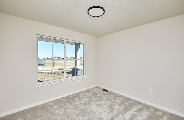 empty room with a textured ceiling and light carpet