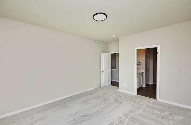 unfurnished bedroom with light colored carpet and connected bathroom