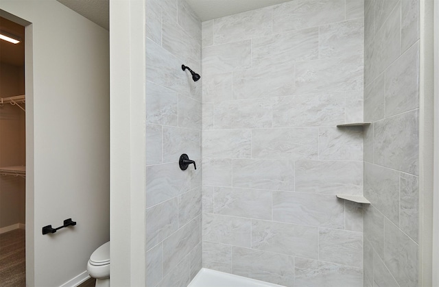 bathroom featuring tiled shower and toilet