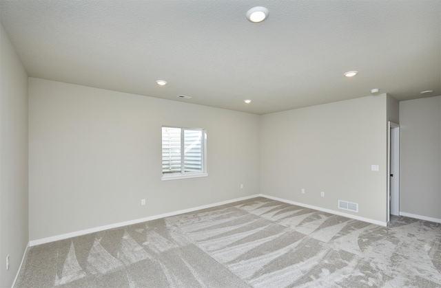 carpeted empty room with a textured ceiling