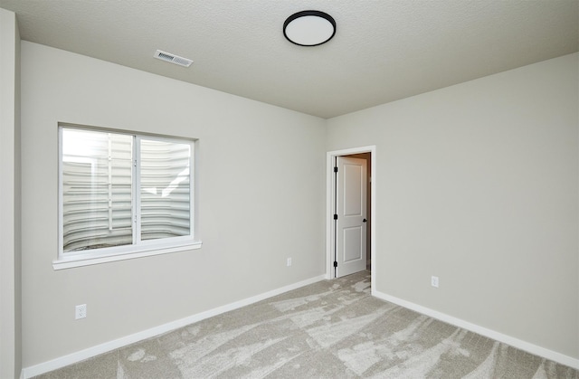 empty room featuring light colored carpet and a textured ceiling