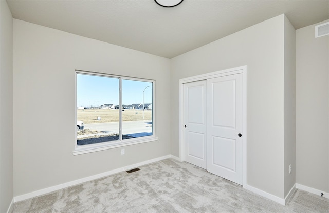 unfurnished bedroom featuring a closet and light carpet