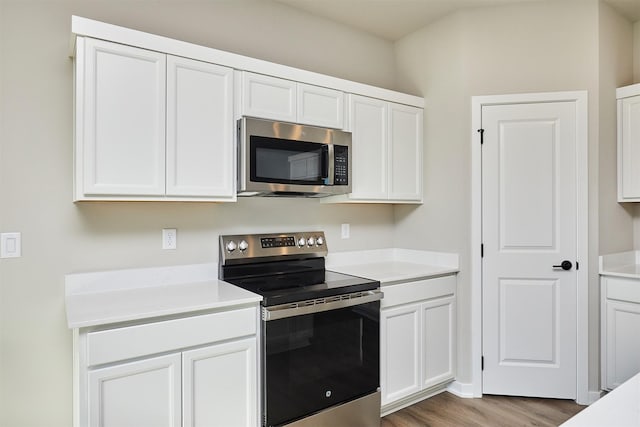 kitchen with white cabinets, appliances with stainless steel finishes, and light hardwood / wood-style flooring