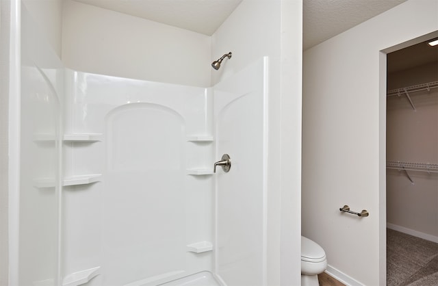 bathroom featuring walk in shower, toilet, and a textured ceiling