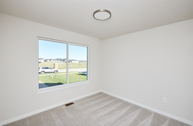 carpeted spare room with a textured ceiling