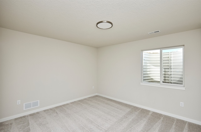 carpeted empty room with a textured ceiling