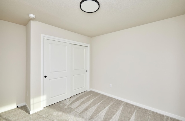 unfurnished bedroom with light carpet and a closet