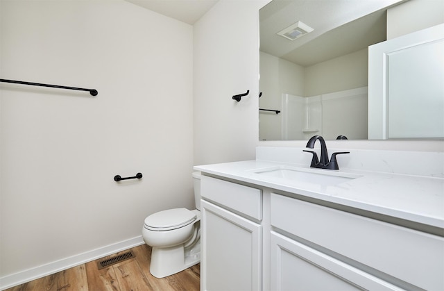 bathroom with hardwood / wood-style floors, vanity, toilet, and a shower