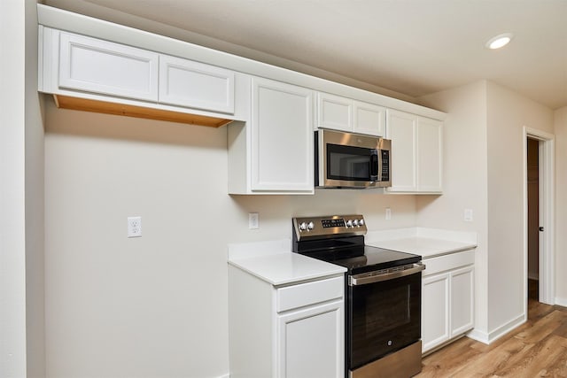 kitchen featuring appliances with stainless steel finishes, light hardwood / wood-style floors, and white cabinetry