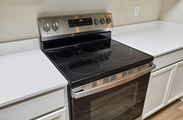 kitchen with white cabinets, stainless steel range with electric cooktop, and light wood-type flooring