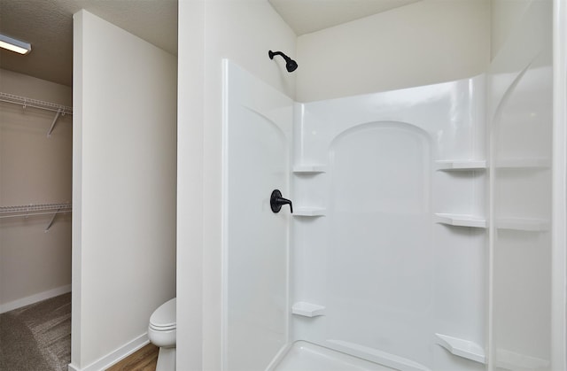 bathroom featuring toilet, a textured ceiling, and walk in shower