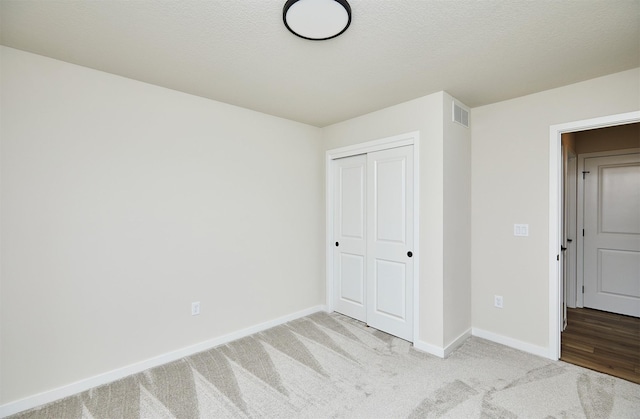 unfurnished bedroom with a closet and light colored carpet