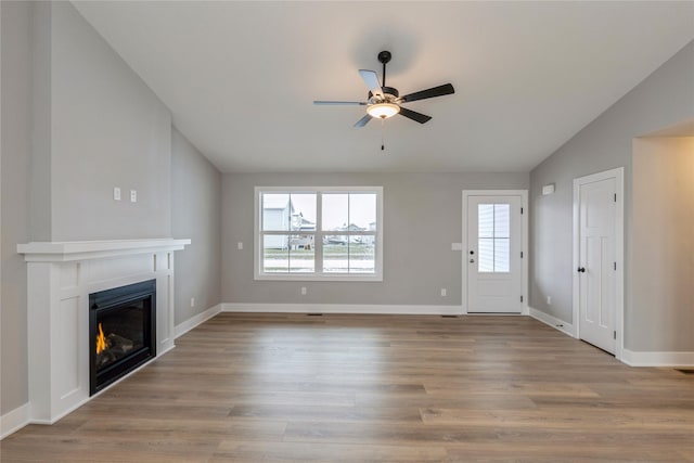 unfurnished living room featuring lofted ceiling, light wood-type flooring, ceiling fan, and a healthy amount of sunlight