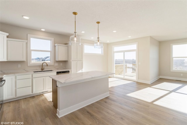 kitchen with plenty of natural light, a kitchen island, white cabinetry, and sink