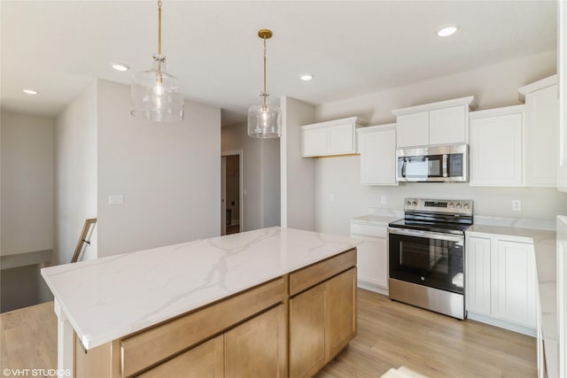 kitchen with a center island, light stone countertops, appliances with stainless steel finishes, light hardwood / wood-style floors, and white cabinetry