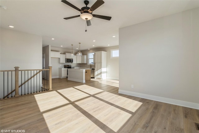 unfurnished living room with ceiling fan, sink, and light hardwood / wood-style flooring