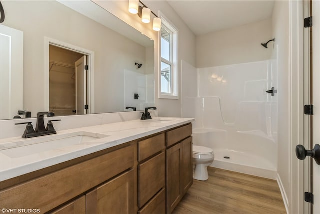 bathroom featuring a shower, vanity, hardwood / wood-style flooring, and toilet