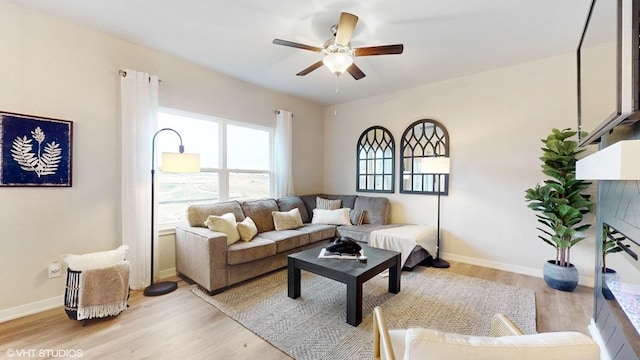living area featuring light wood-style floors, baseboards, and ceiling fan