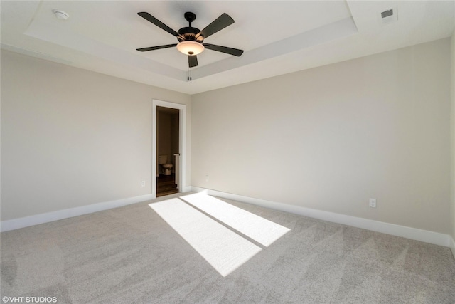 spare room featuring ceiling fan, a raised ceiling, and carpet flooring