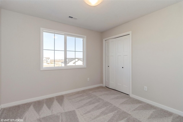 unfurnished bedroom with a closet and light colored carpet