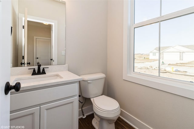 bathroom featuring hardwood / wood-style flooring, a wealth of natural light, toilet, and vanity