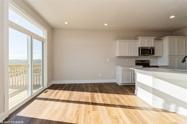 kitchen featuring sink, light hardwood / wood-style flooring, white cabinets, and electric stove