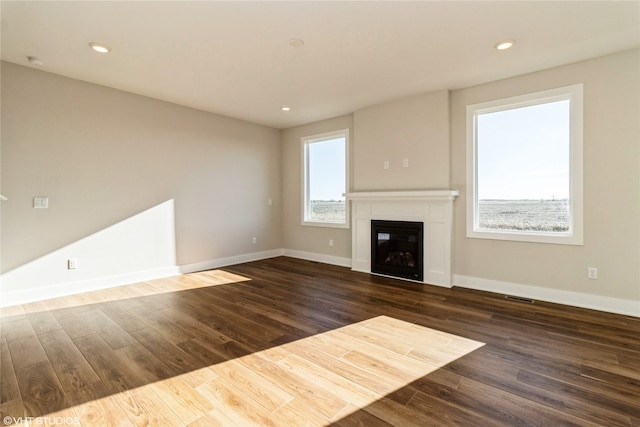 unfurnished living room featuring dark wood-type flooring and a healthy amount of sunlight