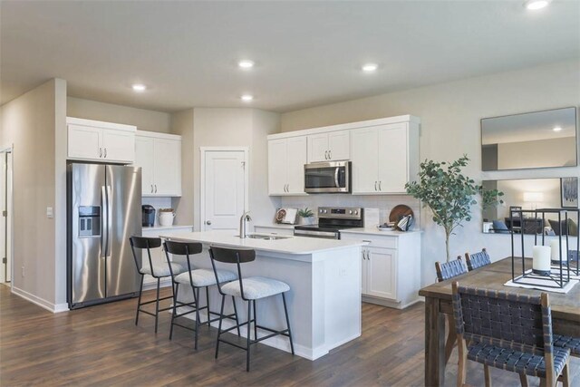 kitchen featuring appliances with stainless steel finishes, white cabinetry, dark hardwood / wood-style flooring, an island with sink, and sink