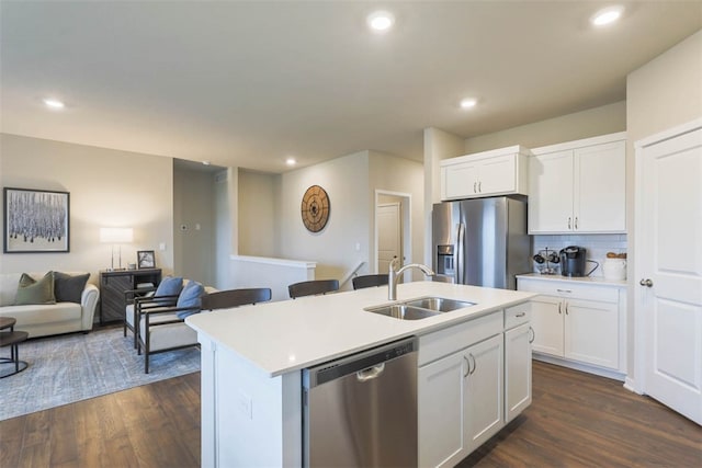 kitchen with white cabinets, dark hardwood / wood-style flooring, stainless steel appliances, sink, and a center island with sink