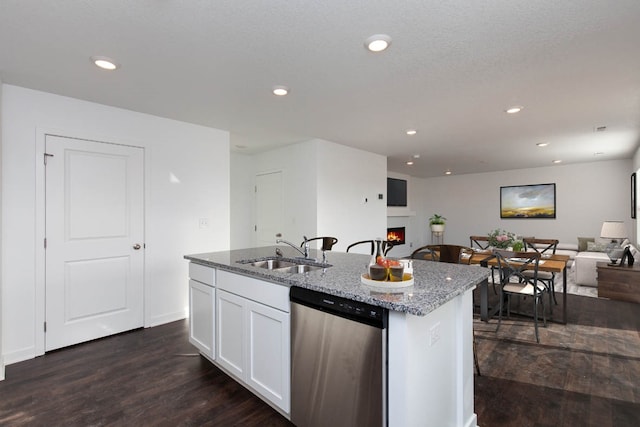 kitchen with white cabinetry, a kitchen island with sink, stainless steel dishwasher, light stone counters, and sink