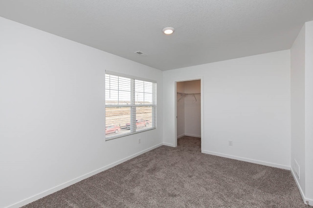 unfurnished bedroom featuring a spacious closet, a closet, and carpet flooring