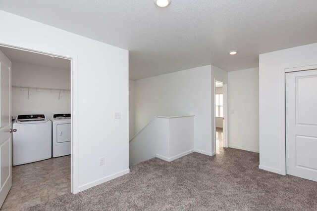 interior space with light colored carpet, a textured ceiling, and independent washer and dryer