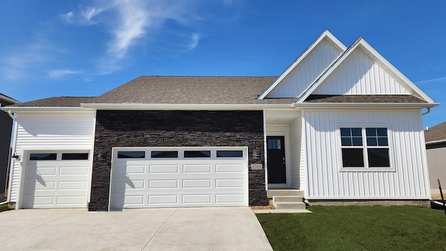 view of front of property with concrete driveway, an attached garage, stone siding, and roof with shingles