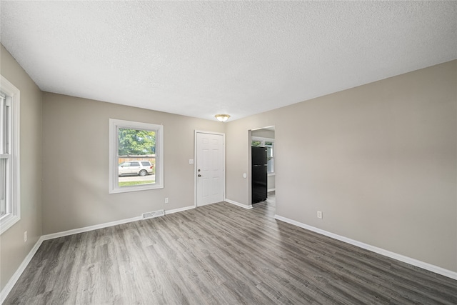 spare room featuring hardwood / wood-style flooring and a textured ceiling